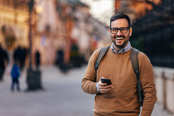 Fototapeta premium Portrait of laughing, caucasian man with backpack, getting a nice message.