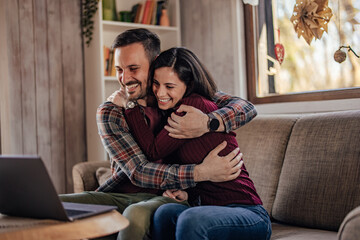 Obraz premium The lovely smiling couple, talking to their friends on the video