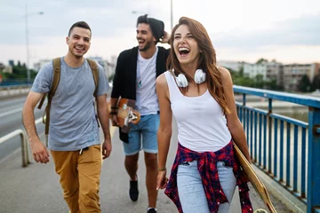 Keuken spatwand met foto Group of happy teen people hang out together and enjoying skateboard outdoors. © NDABCREATIVITY
