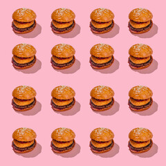 Creative burger pattern with beef patty, camembert and cherry on a pink background. minimal style