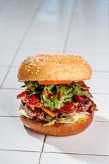 Juicy burger with marbled beef patty, cheddar cheese, bacon, arugula, lettuce, lingonberry sauce