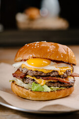 Double patty burger with marbled beef, bacon, cheddar cheese, fried egg, tomatoes, onions, cream...