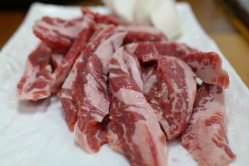 Raw beef ribs are served on a white plate.