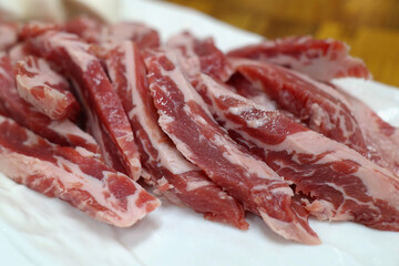 Raw beef ribs are served on a white plate.