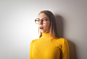 young woman with astonished expression leaning against a wall