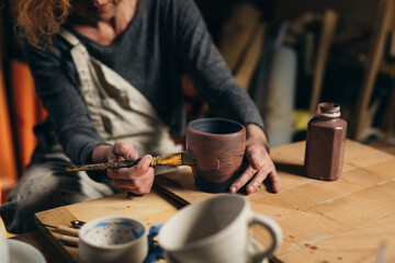 Obraz na płótnie Canvas woman carving pottery in her workshop