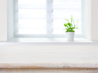 Window with flower pot as blurred background for wooden table