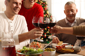 Happy family clinking glasses of wine at festive dinner, focus on hands. Christmas celebration