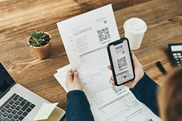 Woman paying invoice scanning QR code from document using fast secure payment system and smartphone QR scanner. Business woman paying bills using express payment technology. Paying expenses online - obrazy, fototapety, plakaty
