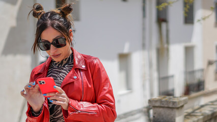 Influencer mujer joven con chaqueta roja visionando sus likes antes de una sesión de fotos