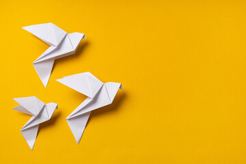 White origami doves as a symbol of faith, hope and peace on a yellow background