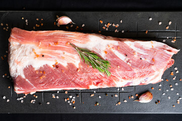 Raw ribs with rosemary on a black board