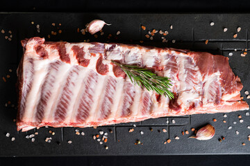 Raw ribs with rosemary on a black board