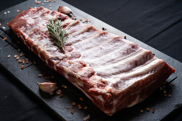 Raw ribs with rosemary on a black board