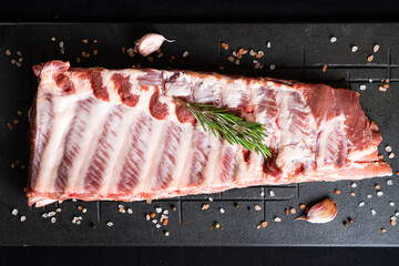 Raw ribs with rosemary on a black board