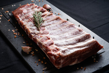 Raw ribs with rosemary on a black board