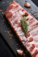 Raw ribs with rosemary on a black board