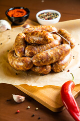 Sausages on a wooden and paper board with garlic and chili pepper