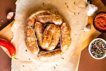 Sausages on a wooden and paper board with garlic and chili pepper