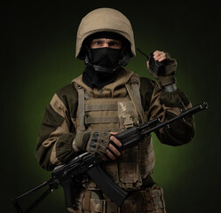 a Russian soldier in military clothes with a Kalashnikov assault rifle on a dark background takes...