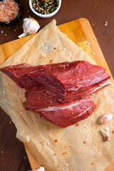 raw meat with pepper , garlic and salt on paper and wooden board