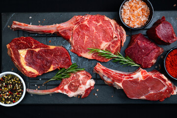 raw meat on a black board with salt, pepper and rosemary
