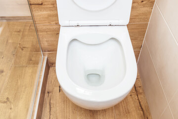 Clean toilet bowl with open lid in toilet, hygiene concept. View from above.