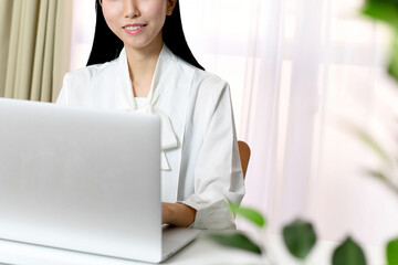 笑顔でパソコン操作するアジア人の女性