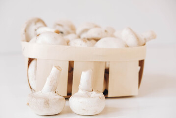 Champignon mushrooms in a wicker basket on a white background
