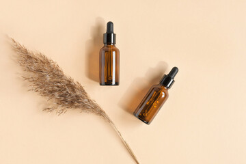 Dark amber glass bottle on beige background. Pampas grass. Natural skin care SPA beauty product design. Mineral organic oil cosmetics. Minimal Mock-Up. Oily pipette. Face and body treatment. Flat lay