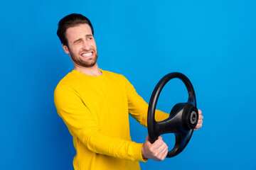 Portrait of attractive worried guy holding steering wheel negative reaction isolated over bright...