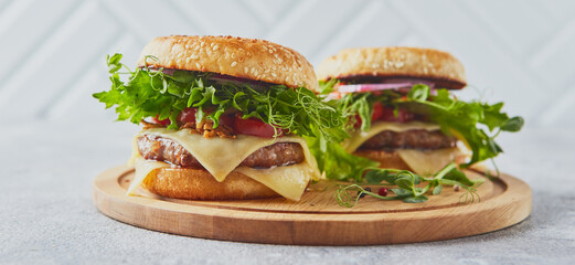 Two burgers with veal cutlet and herbs on wooden cutting board