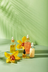 Cosmetic care products in glass bottles with orchid flowers - serums, cream, gel, oils. Concept for face and body care, wellness and spa, tropical relaxation.