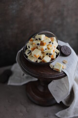White chocolate candies with nuts, dried fruits and chocolate chip cookies. Homemade fudge in a vintage plate