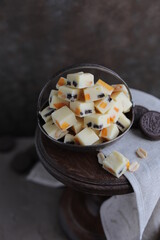 White chocolate candies with nuts, dried fruits and chocolate chip cookies. Homemade fudge in a vintage plate