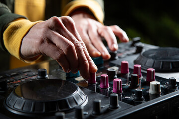 manos DJ mezclando musica en una mesa de mezclas fiesta en el bosque por la noche close-up, rave...