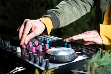 manos DJ mezclando musica en una mesa de mezclas fiesta en el bosque por la noche close-up, rave party - obrazy, fototapety, plakaty
