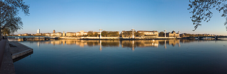 Fototapeta premium View of Lyon from the river bank Rhone, historical buildings, city center, with centre Nautique in background at the sunset. Lyon France