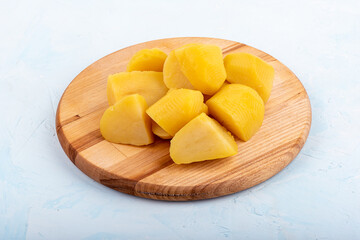 Boiled and chopped potatoes on a wooden cutting board.