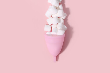 Pink menstrual cup and white mini marshmallow like blood drop with shadow on pink background. Women's health, alternative hygiene and ecology of planet. Top front view, copy space, flat lay.