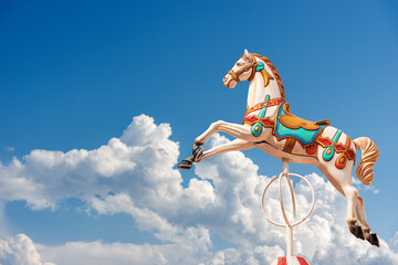 Close-up of a Carousel Horses or Merry-go-round against a beautiful clear blue sky with clouds and copy space. Italy, Europe. © Alberto Masnovo