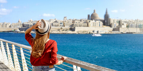 Traveling in Europe. Panoramic view of female tourist holding hat looking at the city of Valletta, Malta. © zigres
