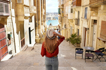 Holidays in Malta. Back view of traveler woman descends stairs in the historic city of Valletta,...