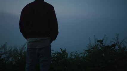 Relaxed man enjoying sunrise in field. Calm guy looking mountain landscape