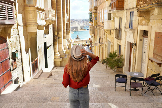 Holidays in Malta. Back view of traveler woman descends stairs in the historic city of Valletta, UNESCO World Heritage, Malta.