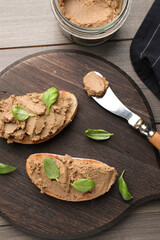 Fototapeta na wymiar Slices of bread with delicious pate and basil on wooden table, flat lay