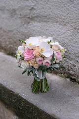 Wedding bouquet on gray stone background. Bridal bouquet composed of roses, freesia, peony and phalaenopsis orchids. Wedding day.