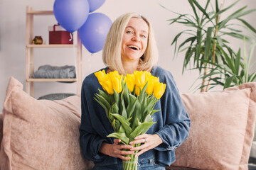 Happy adult woman hold bouquet of flowers at home