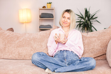 Adult woman sitting on the sofa at home and having a cup of coffee