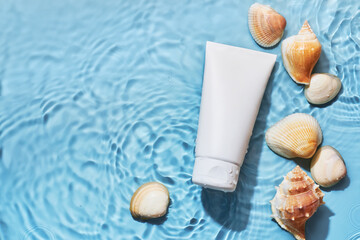 Organic cosmetic product with sea minerals. Skincare treatment cream and shells on blue water background